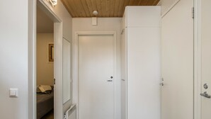 A narrow hallway with a wooden ceiling, a white door, and a radiator on the left.
