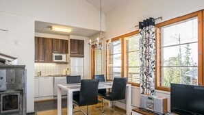 A modern kitchen with a dining area, a flat-screen TV, and a fireplace.