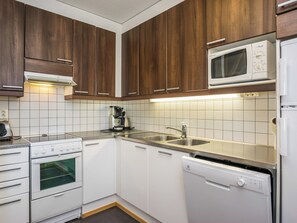 A kitchen with wooden cabinets, a microwave, a stove, a sink, and a dishwasher.
