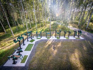 An outdoor gym area with exercise equipment, surrounded by a forest. - Tatunmökki by Interhome (Mikkeli)
