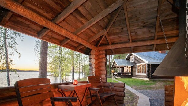 Eine Holzhütte mit verdeckter Veranda, Kamin und Seeblick, sowie eine weitere Hütte.