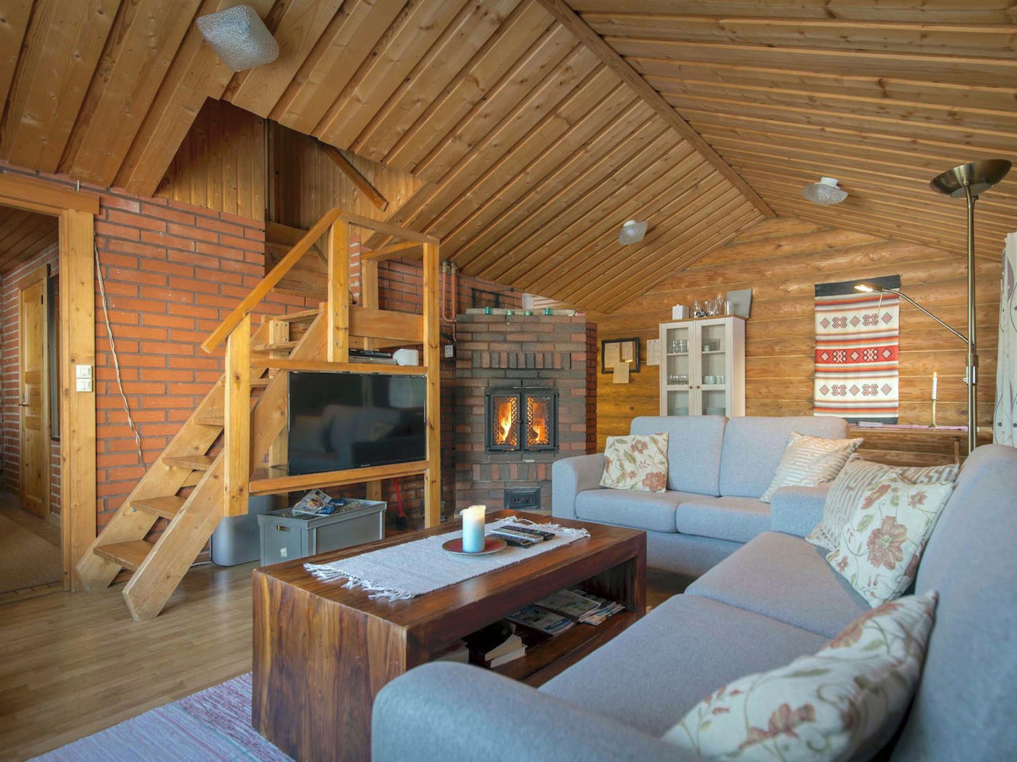 Una sala de estar acogedora con chimenea, televisor, sofá y escalera.