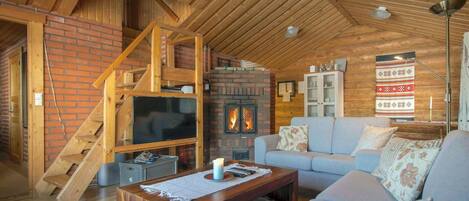 A cozy living room with a fireplace, a television, a sofa, and a staircase.
