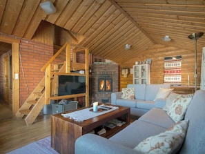 Ein gemütliches Wohnzimmer mit Kamin, Fernseher, Sofa und einer Treppe.