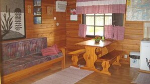 A cozy cabin interior with a wooden bench, a small table, and a sofa. - Takaharju by Interhome (Posio)