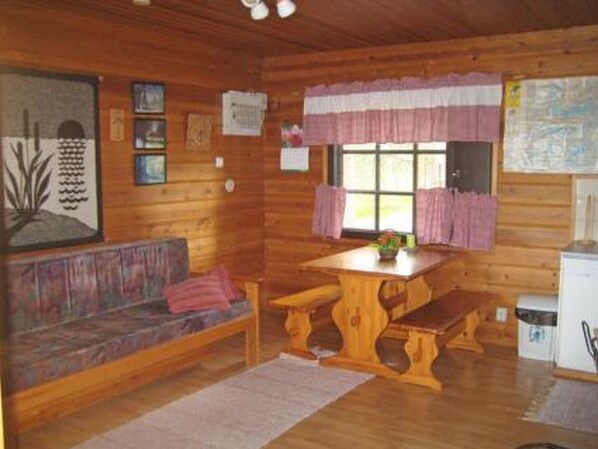 L’intérieur d’un chalet chaleureux, avec un banc en bois, une petite table et un canapé.