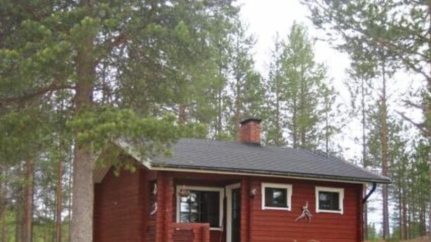 A small, single-story cabin with a chimney, a front porch, and a picnic table with chairs. - Takaharju by Interhome (Posio)