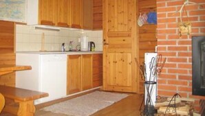 A wooden cabin interior with a kitchen area, including cabinets, a countertop, and a fireplace. - Takaharju by Interhome (Posio)