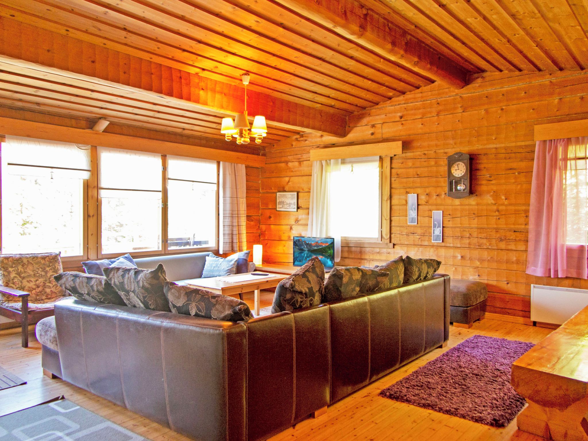 Interior acogedor de una cabaña con un sofá de cuero, paredes de madera y una chimenea.