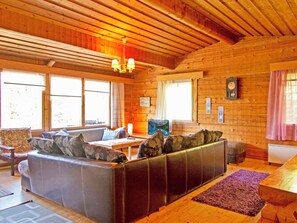 Interior acogedor de una cabaña con un sofá de cuero, paredes de madera y una chimenea.