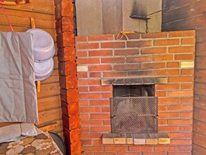 A brick fireplace with a metal screen, a wooden wall, and a hanging cloth.