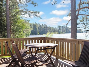 A wooden deck with a table and chairs overlooking a lake and forest. - Jyrkänne by Interhome (Kuopio)