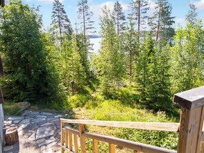 Eine Holzterrasse mit einem steinbelagten Weg, der zu einem bewaldeten Gebiet führt.