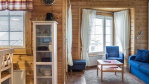 Ein gemütliches Blockhaus-Interieur mit Holzausstattung, einem weißen Schrank mit Glastüren, einem blauen Sofa und einem kleinen Tisch.