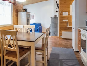Eine gemütliche Küche mit Holzschränken, einem Esstisch mit Stühlen und einem blauen Sofa im Hintergrund.
