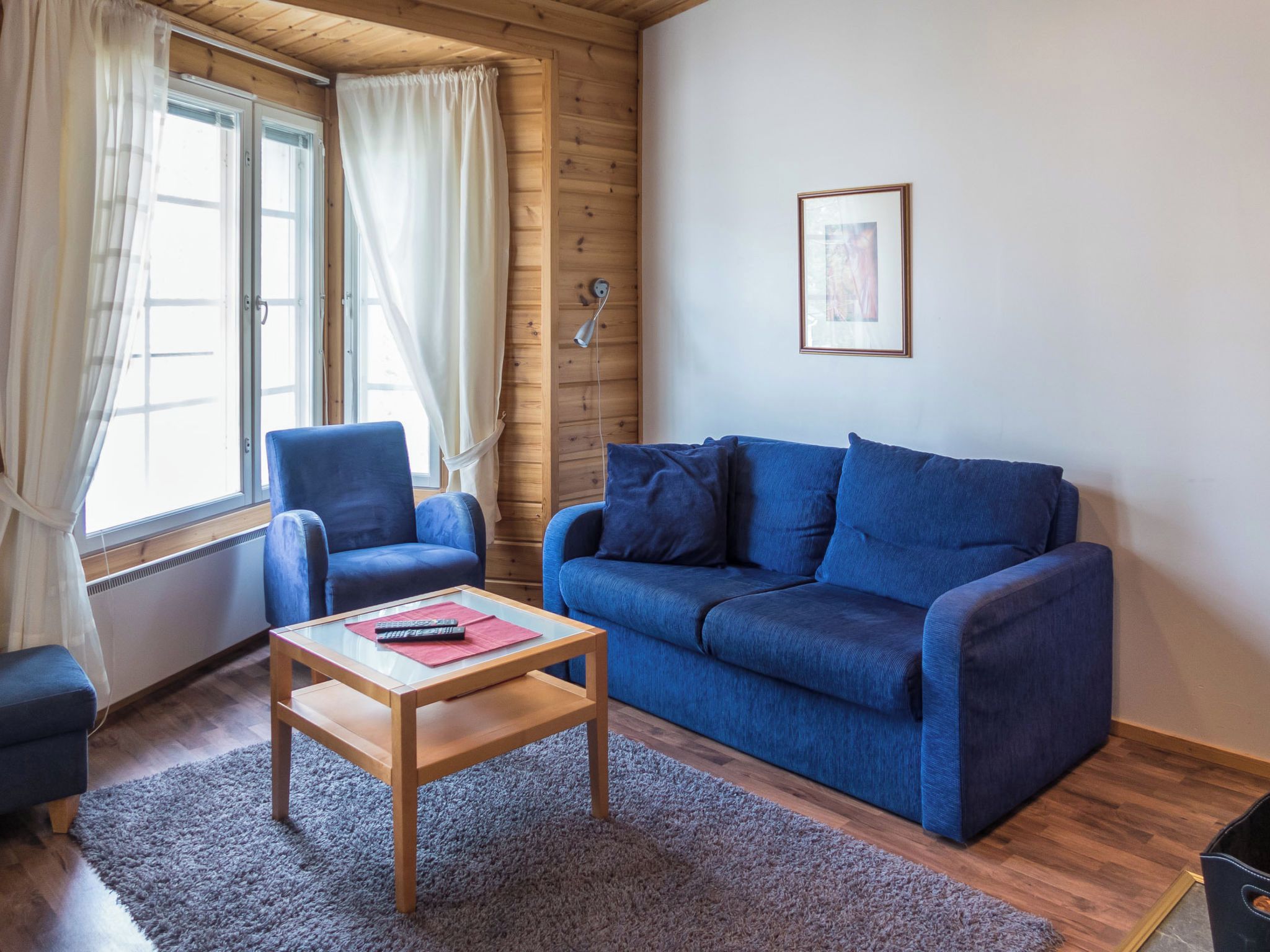 Una sala de estar acogedora con un sofá azul, un sillón a juego y una mesa de centro de madera.
