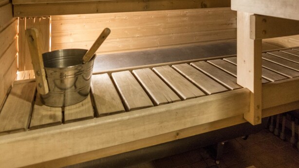 Eine Holzbank mit einem Metallkübel und einem Holzlöffel.