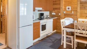 Eine kompakte Küche mit Kühlschrank, Herd, Backofen und Kaffeemaschine.