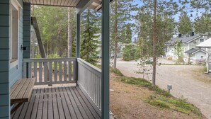 Eine Holzterrasse mit einer Bank, umgeben von Bäumen und einer Schotterauffahrt.