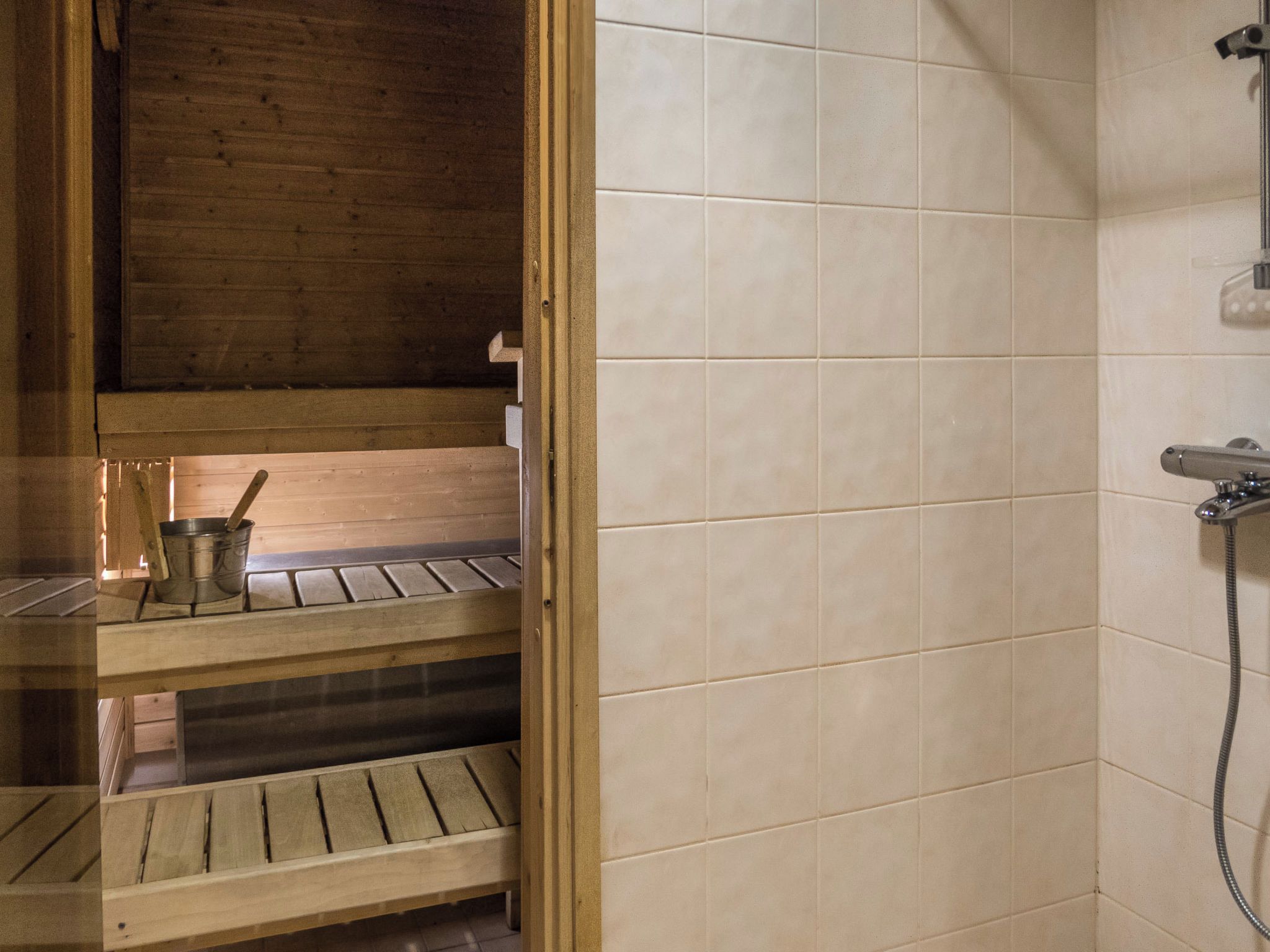 Una sauna de madera con pared de azulejos y zona de ducha.