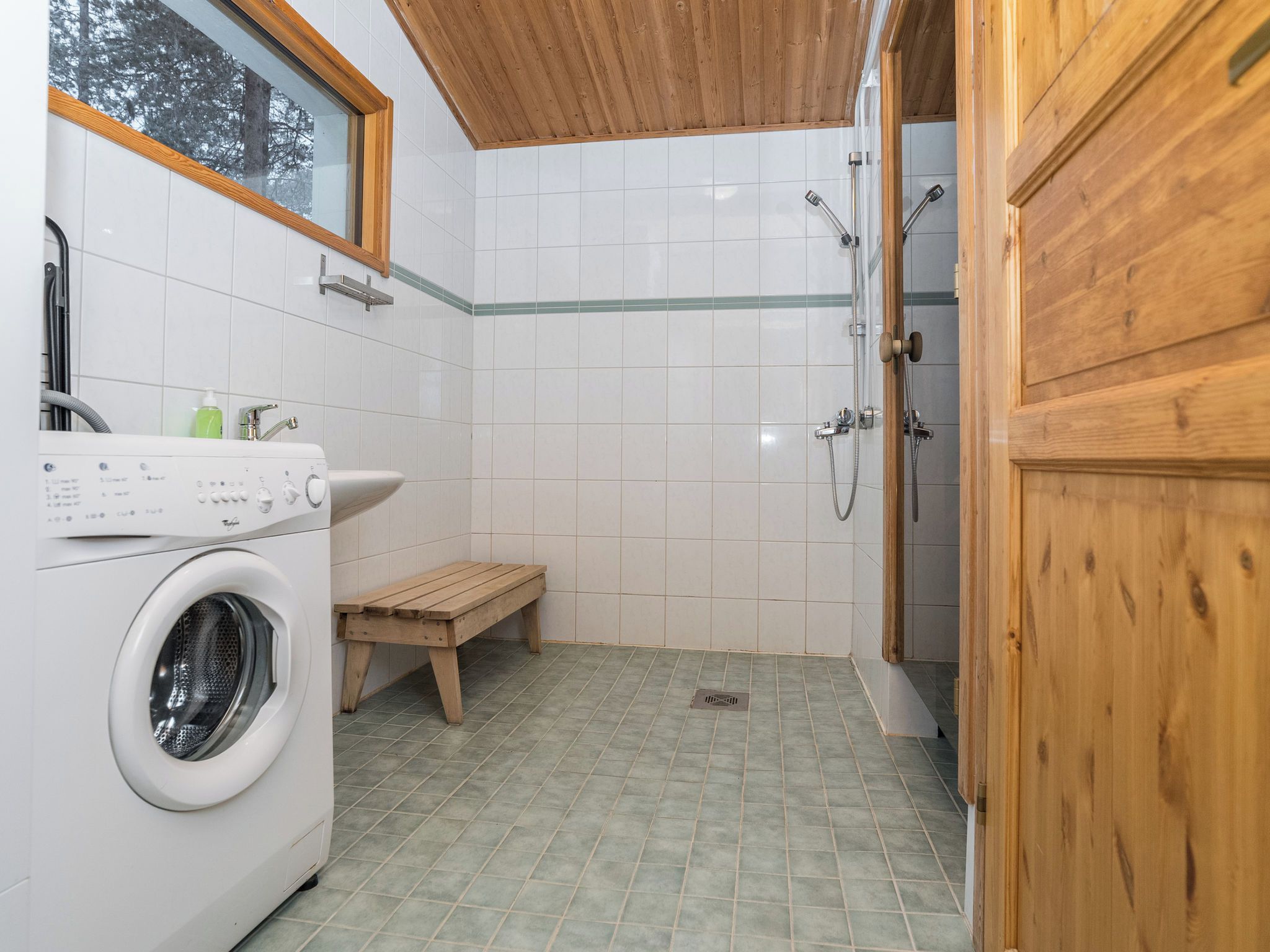 A laundry area with a washing machine, a sink, and a wooden bench.