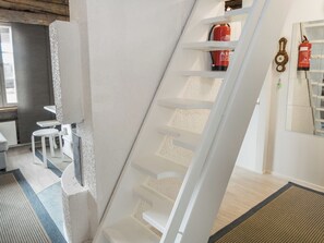 Un intérieur moderne avec un escalier blanc, un coin repas comprenant une table et des chaises, et du matériel de sécurité incendie fixé au mur.
