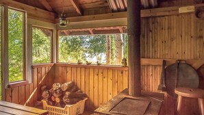 Une cabane en bois avec une véranda, une cheminée en briques et une table en bois.