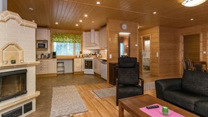 Acogedor interior de cabaña con sala de estar, cocina y chimenea.