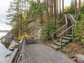 A wooden dock leading to a staircase with a bench, surrounded by trees and a body of water.