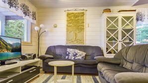 A living room with a sofa, a small round table, a television, and a cabinet. - Kiikkukallio by Interhome (Rautalampi)