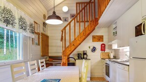 A cozy kitchen with wooden flooring, a dining table with chairs, a staircase, and a refrigerator. - Kiikkukallio by Interhome (Rautalampi)