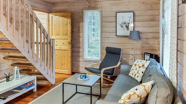 Un interior de madera con una escalera, un sofá, una silla y una mesa.