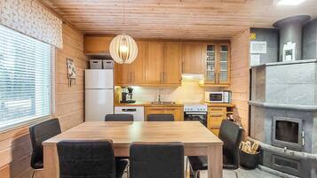 Une cuisine compacte avec des meubles en bois, une table à manger avec des chaises, un réfrigérateur, une cuisinière et un four à micro-ondes.