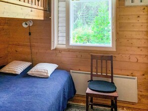 Una habitación con una cama, una silla y un ventanal con persianas.