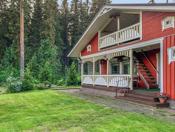 A two-story red house with a covered porch and a staircase leading to the upper level.