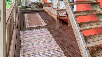 A wooden deck with a bench, a table, and a rug.