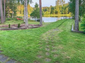 Un área verde bien cuidada con una terraza de madera y un lago al fondo.