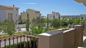 Zona residencial con edificios modernos, cielo despejado y un jardín bien cuidado con palmeras.