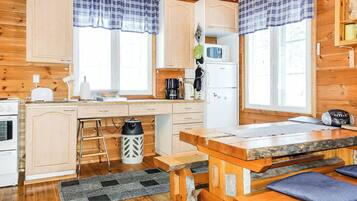 Een keuken in chaletstijl met houten kastjes, een centraal eiland en een eettafel.