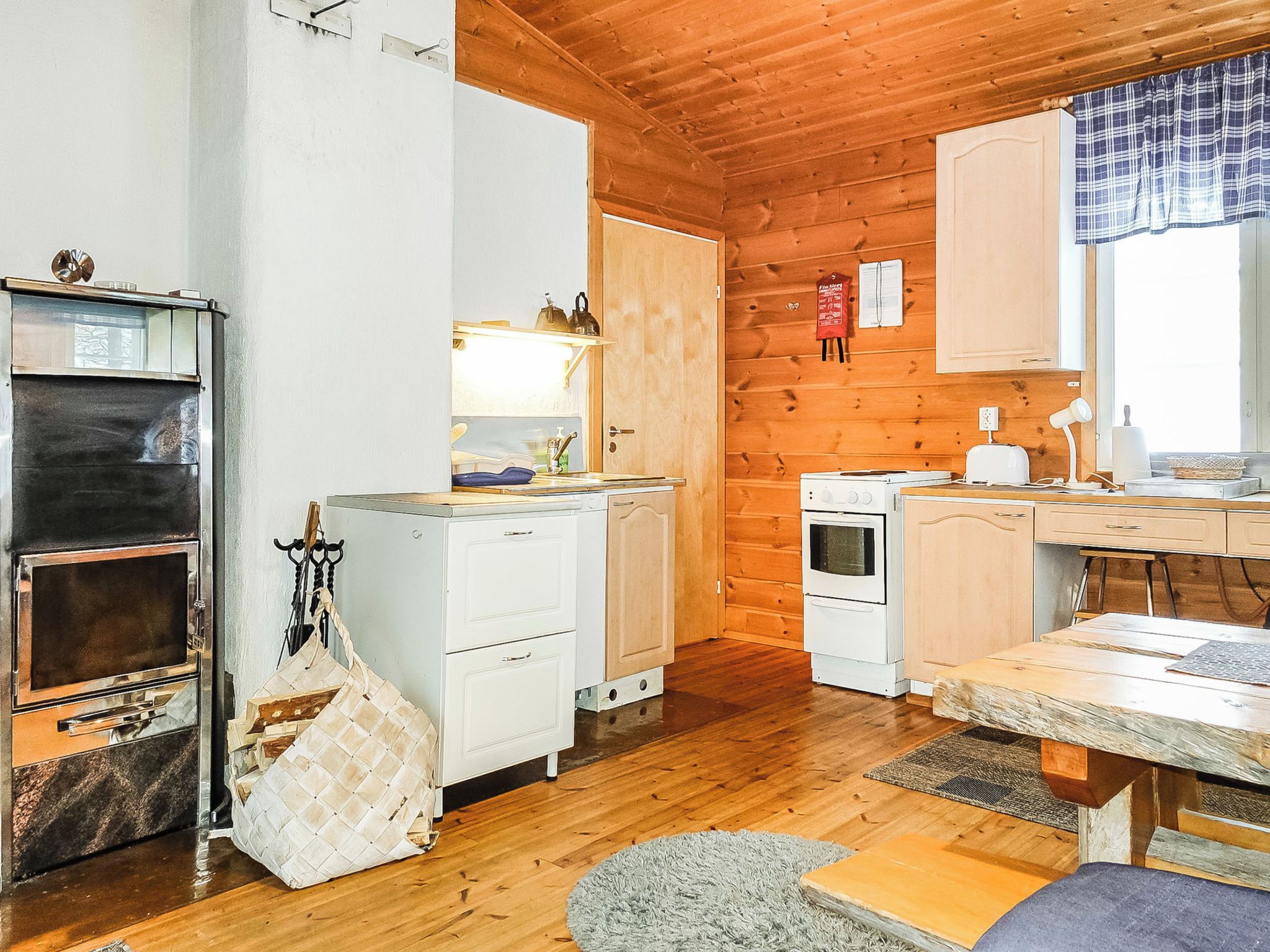 A compact kitchen with wooden walls, a built-in oven, a stove, and a small countertop.
