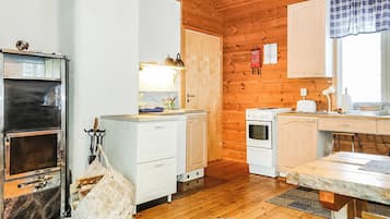 A compact kitchen with wooden walls, a built-in oven, a stove, and a small countertop.