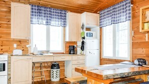 A cozy cabin-style kitchen with wooden cabinets, a central island, and a refrigerator. - Hoviranta by Interhome (Inari)