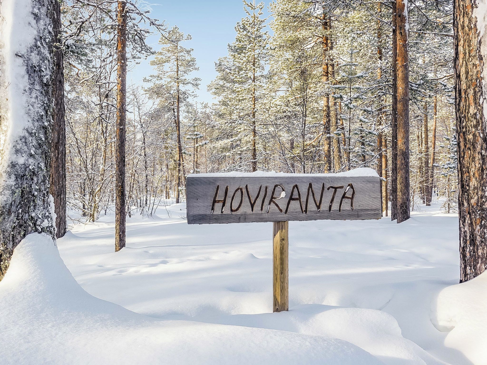 A wooden sign with the text 'HOVIKANTA' in a snowy forest setting.
