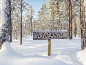 Een houten bord met de tekst 'HOVIKANTA' in een besneeuwd bos.