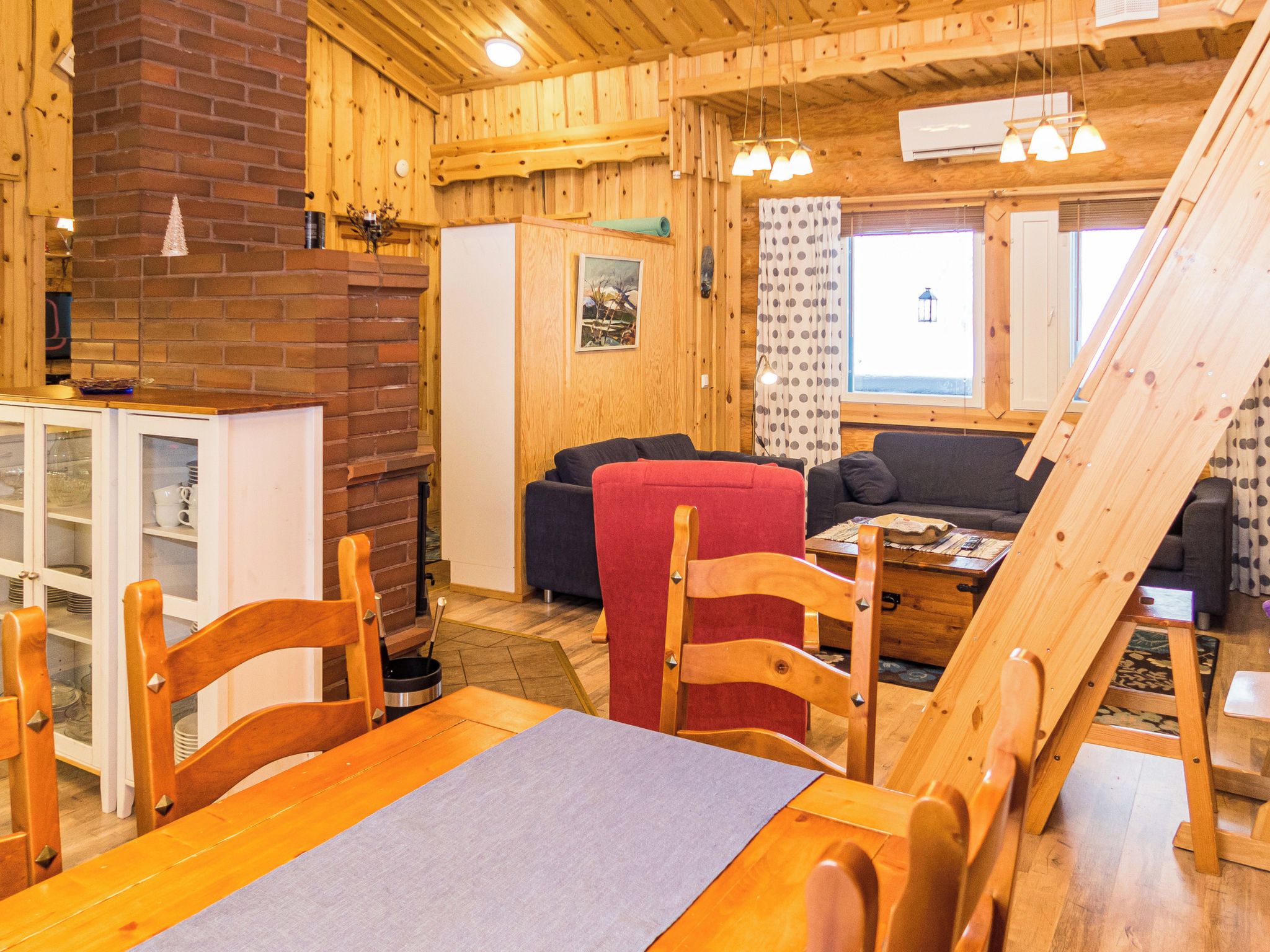 L’intérieur chaleureux d’un chalet comprend un coin repas, une cheminée et un salon avec un canapé et des fauteuils.