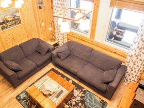 Una habitación acogedora con dos sofás, una mesa de centro de madera y una ventana con cortinas.