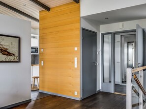 A modern interior with a wooden partition, a grey door, and a staircase with a glass railing. - Rukavuorenhuippu 23 a by Interhome (Kuusamo)