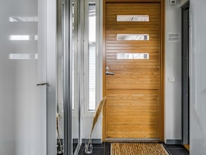 Et moderne interiør med en trädør, en glasdør og et sort flisegulv.