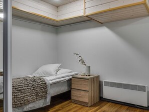 A bedroom with a bed, bedside table, and radiator. - Rukavuorenhuippu 23 a by Interhome (Kuusamo)