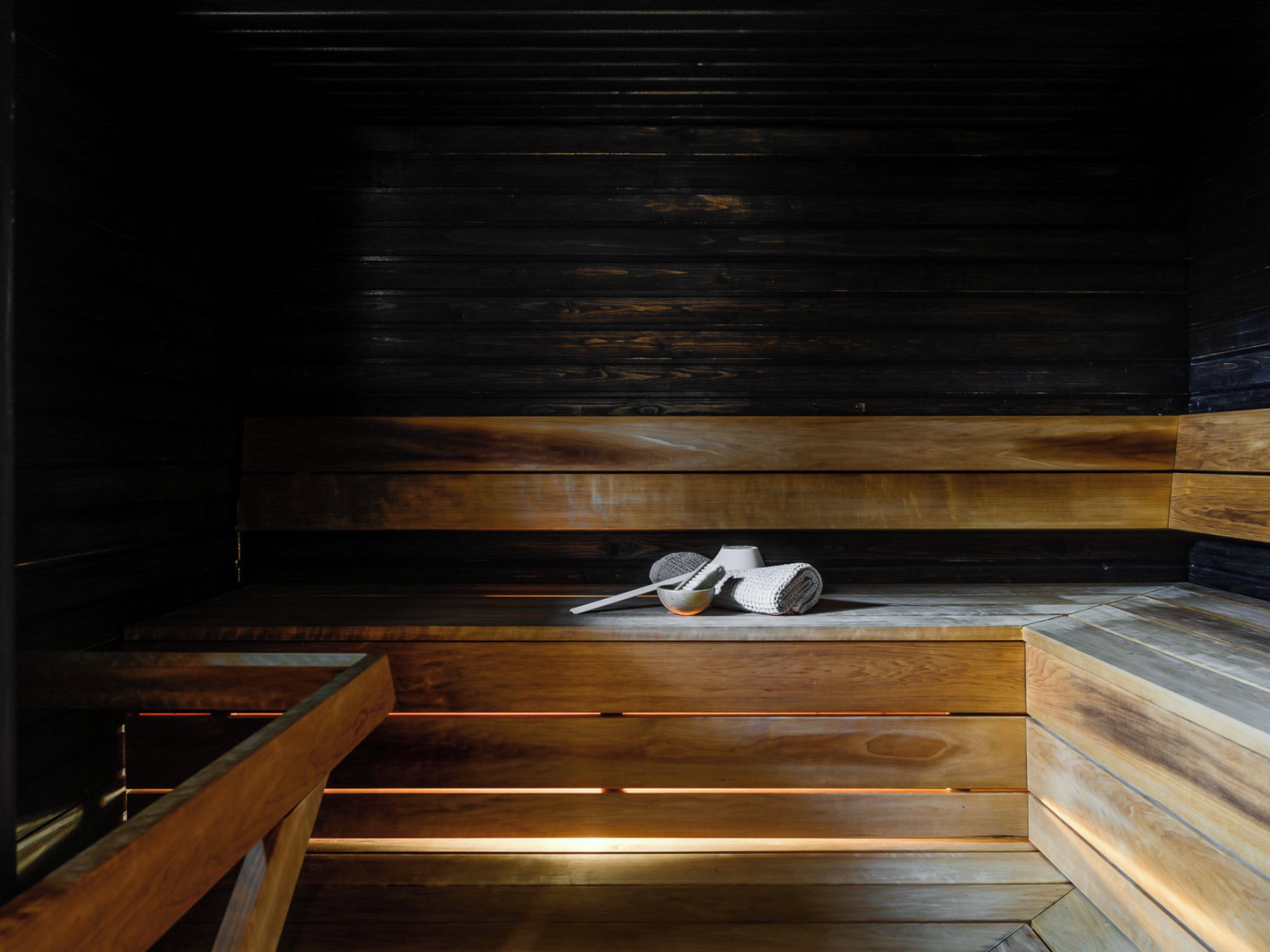 Un sauna avec des bancs en bois et une banquette.